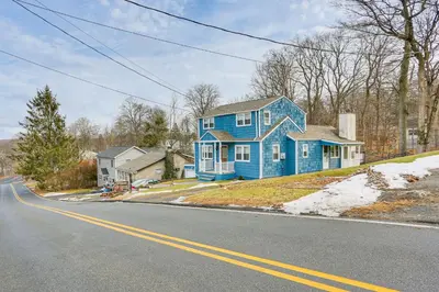 a blue house sitting on the side of a road at Walk to Lake Hopatcong Vibrant Home with Deck! in Hopatcong