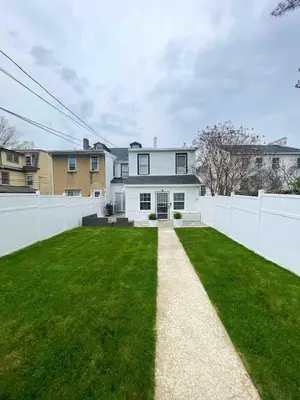 a house with a white fence and a green yard at Chic Phoenixville Retreat With Parking in Phoenixville