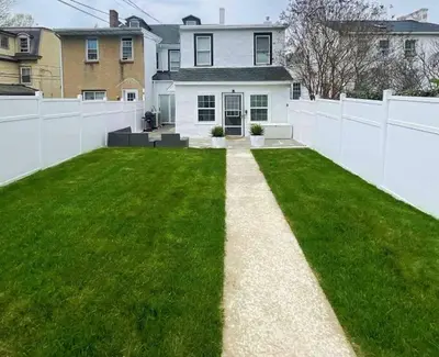 a backyard with a white fence and green grass at Chic Phoenixville Retreat With Parking in Phoenixville