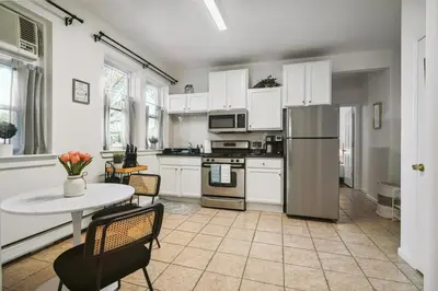 a kitchen with white cabinets and a table with chairs at NYC Escape Easy Transit Easy Parking Quiet Area in Teaneck