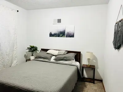 a white bedroom with a bed and a plant at Woodside Haven - Game Room - Central AC - Pet Friendly in Tobyhanna