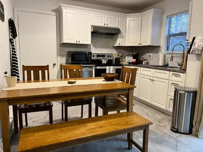 a kitchen with white cabinets and a wooden table and chairs at Woodside Haven - Game Room - Central AC - Pet Friendly in Tobyhanna