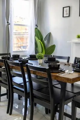 a dining room table with black chairs and a table with pots and pans at 3BR duplex near MetLife! w/ Parking! mins to NY in Jersey City
