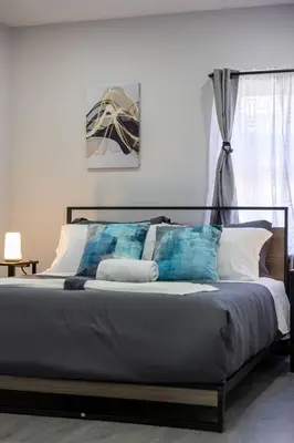 a bedroom with a large bed with blue and white pillows at 3BR duplex near MetLife! w/ Parking! mins to NY in Jersey City