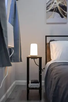 a lamp on a table next to a bed at 3BR duplex near MetLife! w/ Parking! mins to NY in Jersey City