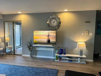 a living room with a tv and a clock on the wall at comfort for you in Elkins Park