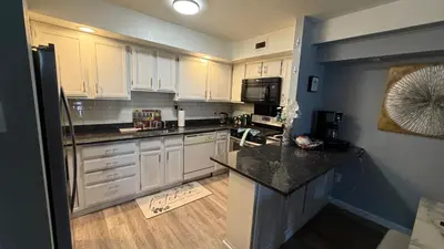 a kitchen with white cabinets and a black counter top at comfort for you in Elkins Park