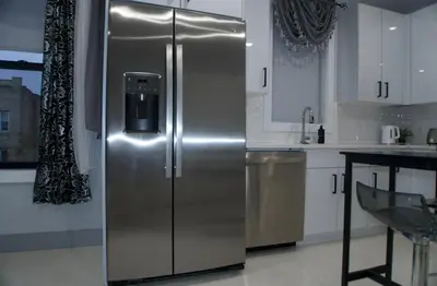 a stainless steel refrigerator in a kitchen with white cabinets at Big Apple room 34 in West New York
