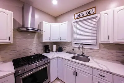 a kitchen with white cabinets and a sink and a stove at Elegant 3BR Stay | Mins to NYC • Near Dream Mall in Newark