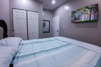 a bedroom with a large bed with a tv on the wall at Elegant 3BR Stay | Mins to NYC • Near Dream Mall in Newark