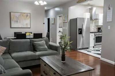 a living room with a couch and a kitchen at Elegant 3BR Stay | Mins to NYC • Near Dream Mall in Newark
