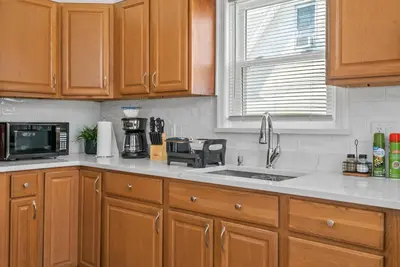 a kitchen with wooden cabinets and a sink and a microwave at Cozy Retreat 15Min to NYC, FIFA, Mall,FREE Parking - Apartment in North Bergen