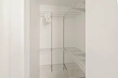 a white closet with white shelves in a room at Cozy Retreat 15Min to NYC, FIFA, Mall,FREE Parking - Apartment in North Bergen