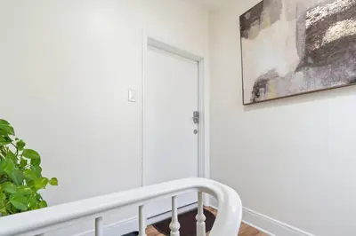 a white staircase in a house with a painting on the wall at Cozy Retreat 15Min to NYC, FIFA, Mall,FREE Parking - Apartment in North Bergen
