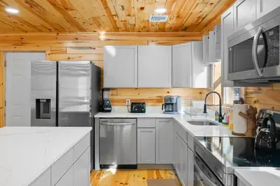 a kitchen with white cabinets and a wooden ceiling at Log Cabin Game Room Close to the Slopes & Lake in Albrightsville