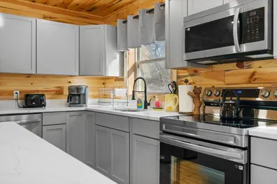 a kitchen with white cabinets and stainless steel appliances at Log Cabin Game Room Close to the Slopes & Lake in Albrightsville