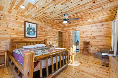 a log cabin bedroom with a bed and a ceiling fan at Log Cabin Game Room Close to the Slopes & Lake in Albrightsville