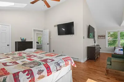 a bedroom with a bed and a flat screen tv at Lakefront Game Room Hot Tub Close to it All in Lake Harmony