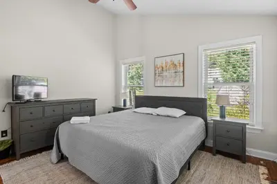 a bedroom with a bed and a tv and two windows at Lakefront Game Room Hot Tub Close to it All in Lake Harmony