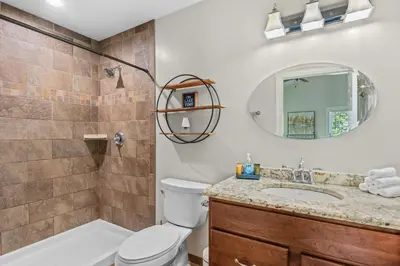 a bathroom with a toilet and a sink and a mirror at Lakefront Game Room Hot Tub Close to it All in Lake Harmony