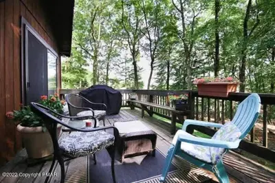 a deck with chairs and a table and a bench at Inn Harmony- Cabin with Game Room Hot Tub Firepit in Lake Harmony