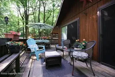 a patio with chairs and a table and an umbrella at Inn Harmony- Cabin with Game Room Hot Tub Firepit in Lake Harmony