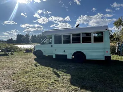 a white bus parked in a grass field at Coastal Style Bus Farm Retreat with Pond Dock and Peaceful Nature Views in Stillwater, Pennsylvania in Stillwater