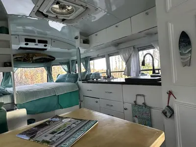 a camper with a table and a kitchen in it at Coastal Style Bus Farm Retreat with Pond Dock and Peaceful Nature Views in Stillwater, Pennsylvania in Stillwater