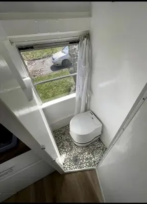 a small bathroom with a toilet and a window at Coastal Style Bus Farm Retreat with Pond Dock and Peaceful Nature Views in Stillwater, Pennsylvania in Stillwater