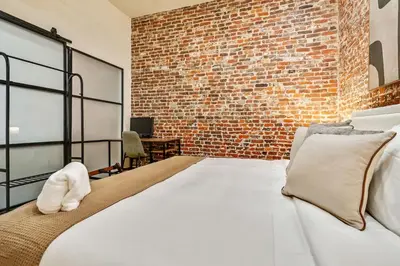 a bedroom with a white bed and a brick wall at Cozy & Historic Old City 2 Bedroom - Sleeps 5 in Philadelphia