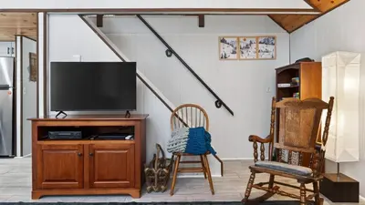 a living room with a tv and two chairs at Evergreen Lodge by AvantStay Poconos Lake Cabin Fireplace Large Deck Near Jack Frost Kalahari in Locust Lakes Village