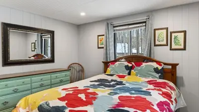 a bedroom with a bed and a dresser and a mirror at Evergreen Lodge by AvantStay Poconos Lake Cabin Fireplace Large Deck Near Jack Frost Kalahari in Locust Lakes Village