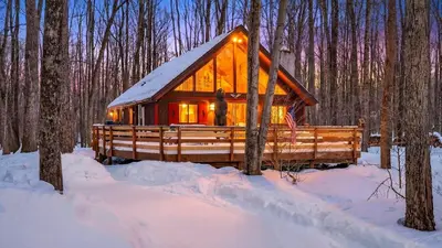a log cabin in the woods in the snow at Evergreen Lodge by AvantStay Poconos Lake Cabin Fireplace Large Deck Near Jack Frost Kalahari in Locust Lakes Village