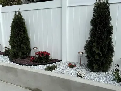 a white fence with two trees in a garden at Luxurious 4BD APT EV Parking in North Bergen
