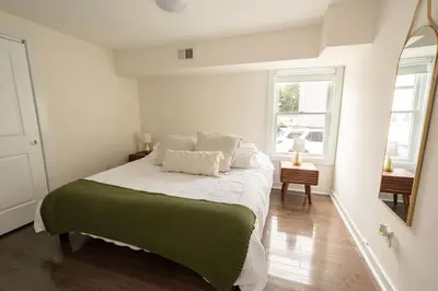 a white bedroom with a bed and a mirror at Luxurious 4BD APT EV Parking in North Bergen