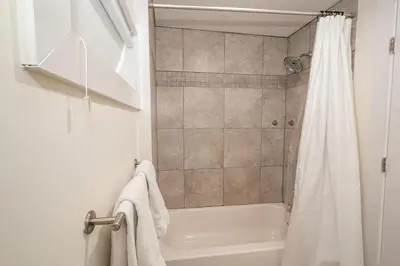 a bathroom with a shower and a white shower curtain at Luxurious 4BD APT EV Parking in North Bergen