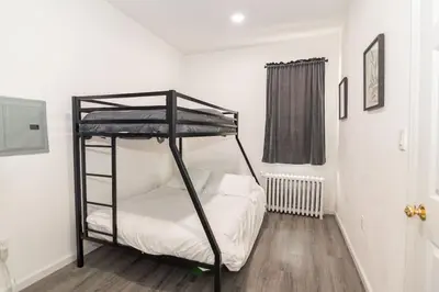a bedroom with a bunk bed with white sheets at Luxury North Bergen 3 BR APT in North Bergen
