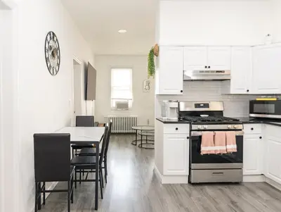 a kitchen with white cabinets and a table with chairs at Luxury North Bergen 3 BR APT in North Bergen