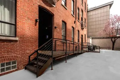 a staircase leading to a brick building with a black door at Eclectic Artisan Loft With Pvt Parking - The Luminaire in Philadelphia