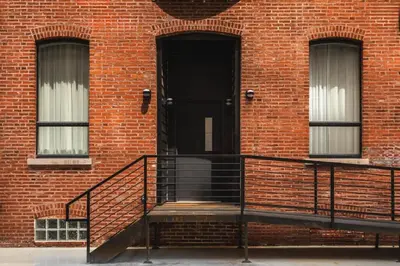a brick building with a staircase and a black door at Eclectic Artisan Loft With Pvt Parking - The Luminaire in Philadelphia