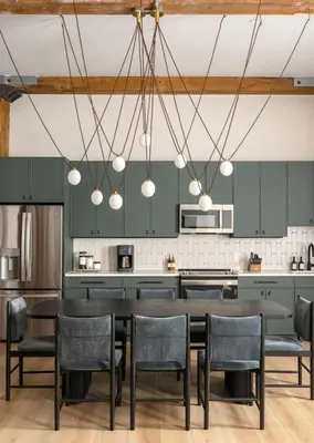 a kitchen with green cabinets and a table and chairs at Eclectic Artisan Loft With Pvt Parking - The Luminaire in Philadelphia