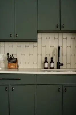 a kitchen with green cabinets and bottles on the counter at Eclectic Artisan Loft With Pvt Parking - The Luminaire in Philadelphia