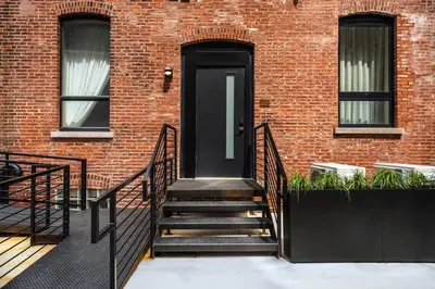 a black door on a brick building with stairs at Elegant Artisan Loft W Private Parking - The Weaver in Philadelphia