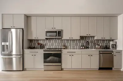 a kitchen with white cabinets and stainless steel appliances at Elegant Artisan Loft W Private Parking - The Weaver in Philadelphia