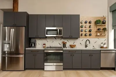 a kitchen with gray cabinets and a stainless steel refrigerator at Stylish Artisan Loft w Chic Design - The Potter in Philadelphia