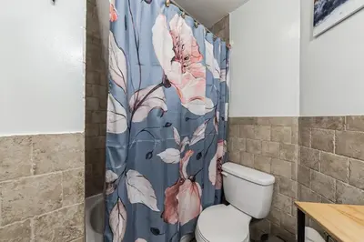 a bathroom with a blue shower curtain with a toilet at Big & Bright 1BR - Center City - Walk Everywhere! in Philadelphia