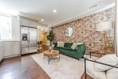 a living room with a green couch and a brick wall at Center City - Modern 2 Bedroom in Philadelphia
