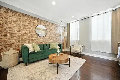 a living room with a green couch and a brick wall at Center City - Modern 2 Bedroom in Philadelphia