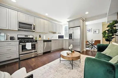 a kitchen with white cabinets and a living room at Center City - Modern 2 Bedroom in Philadelphia