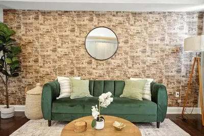 a living room with a green couch and a brick wall at Center City - Modern 2 Bedroom in Philadelphia